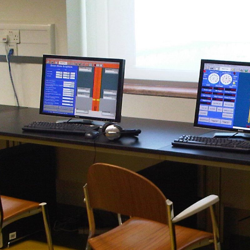 Two computer screens displaying the DrillSIM:5 software-based drilling and well control simulator consoles